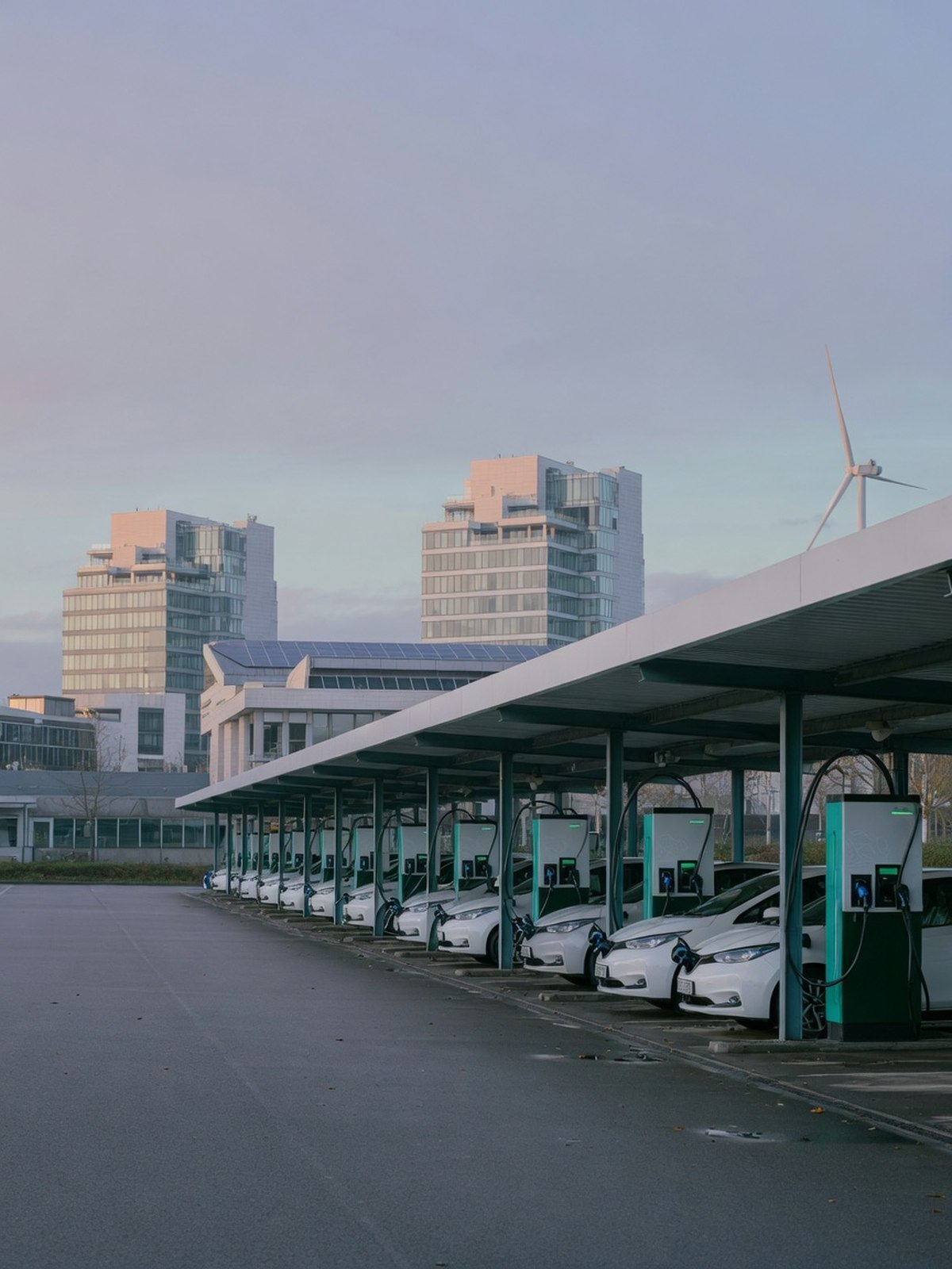 Rangée de véhicules électriques de fonction en recharge sur un site d'entreprise au Luxembourg.