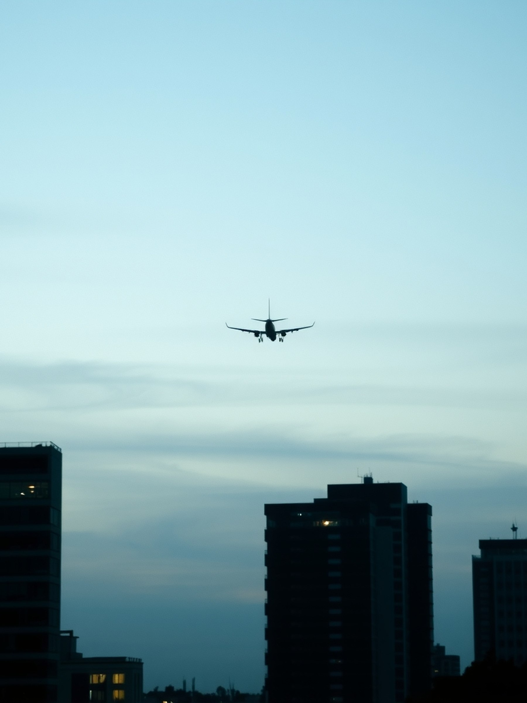 Traînée de condensation blanche se dissipant dans un ciel crépusculaire sobre, vue depuis le sol, sans avion visible de près.